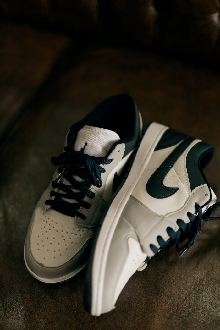 services-05 Close-up of classic black and white sneakers on a leather couch, showcasing modern style.